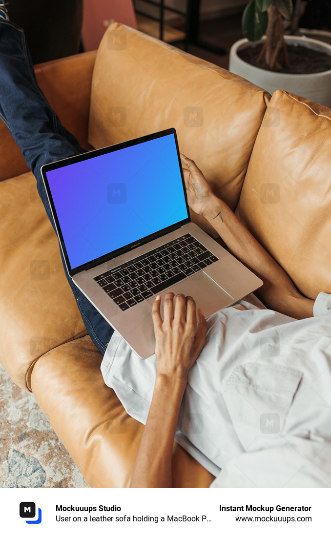 User on a leather sofa holding a MacBook Pro mockup
