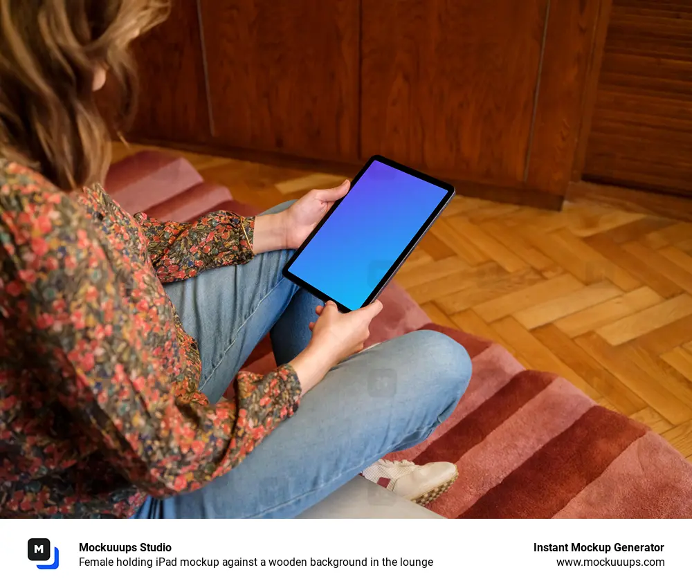 Female holding iPad mockup against a wooden background in the lounge