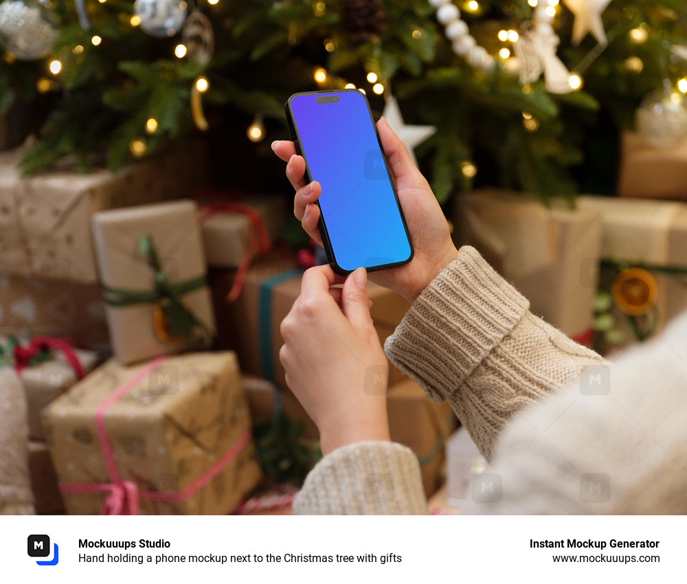 Hand holding a phone mockup next to the Christmas tree with gifts