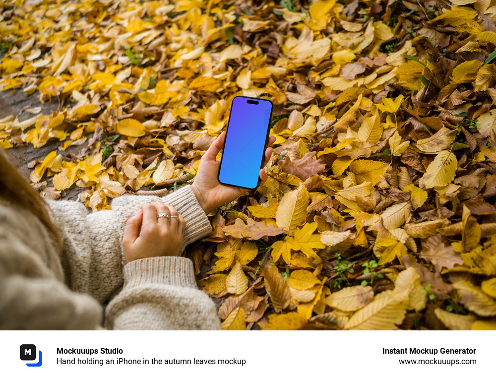 Hand holding an iPhone in the autumn leaves mockup