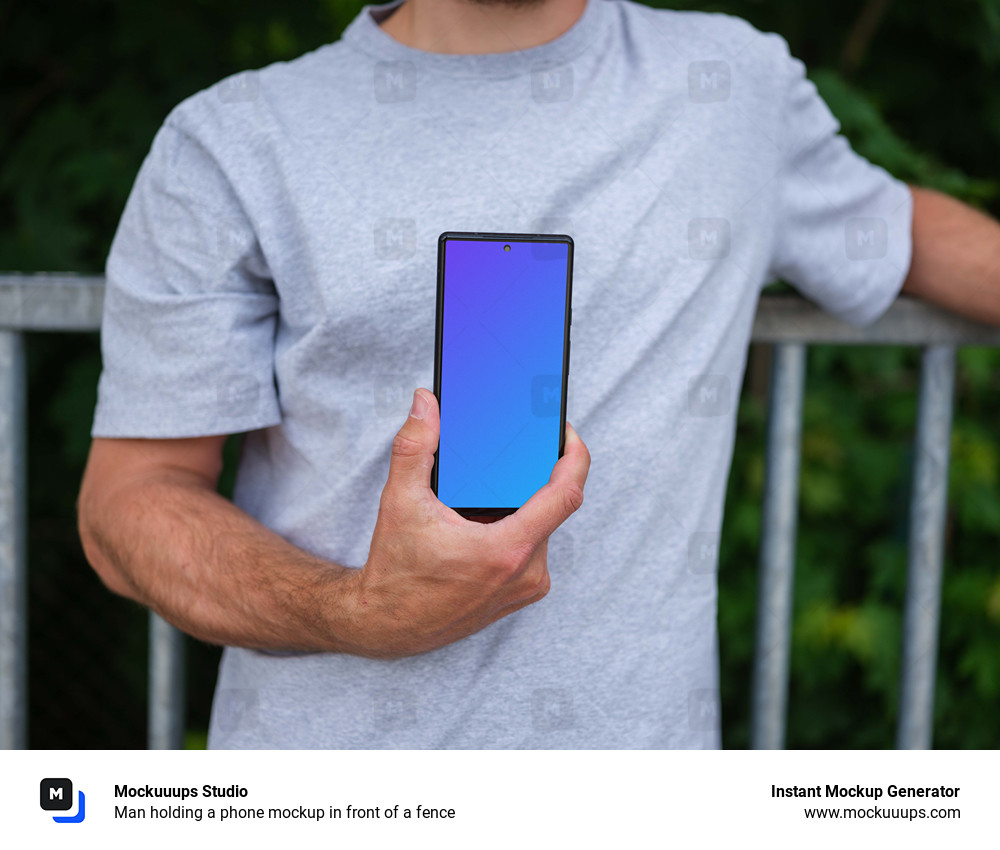 Man holding a phone mockup in front of a fence