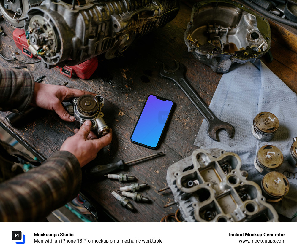 Man with an iPhone 13 Pro mockup on a mechanic worktable