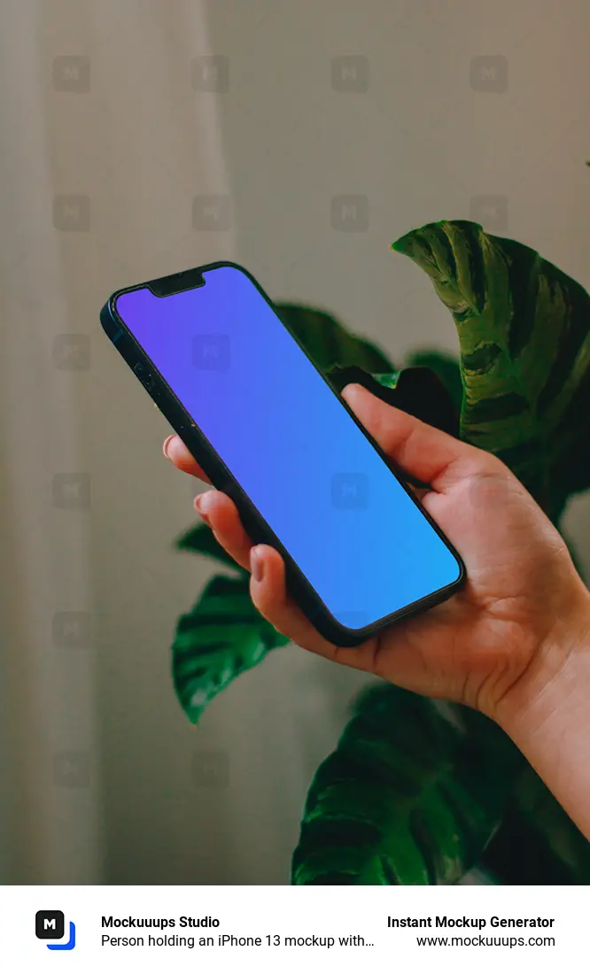 Person holding an iPhone 13 mockup with a plant in the background