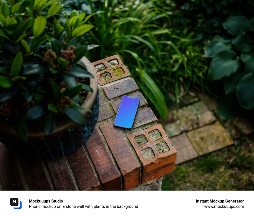 Phone mockup on a stone wall with plants in the background