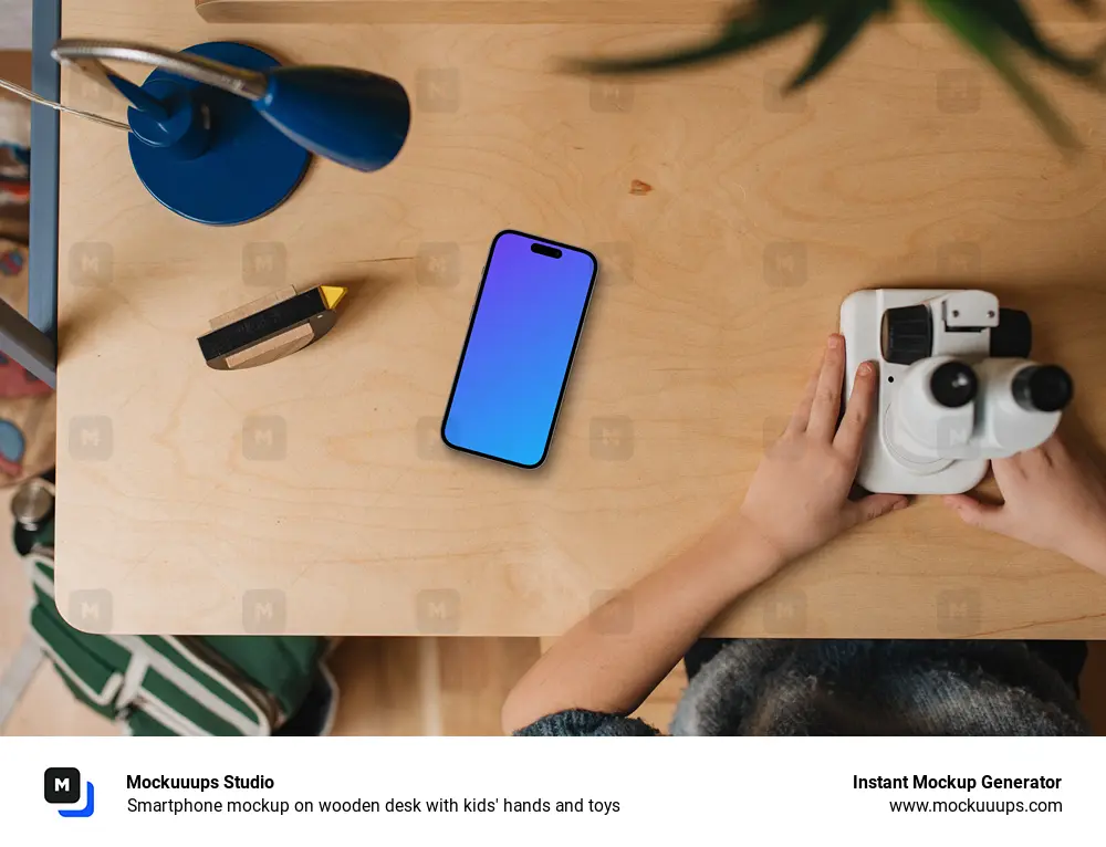 Smartphone mockup on wooden desk with kids' hands and toys