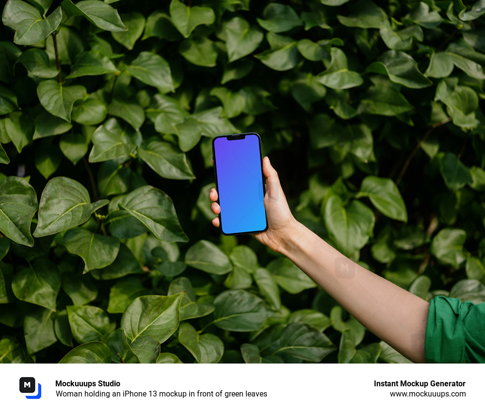 Woman holding an iPhone 13 mockup in front of green leaves