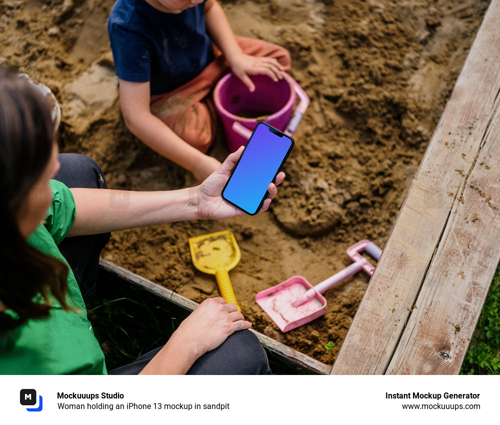 Woman holding an iPhone 13 mockup in sandpit