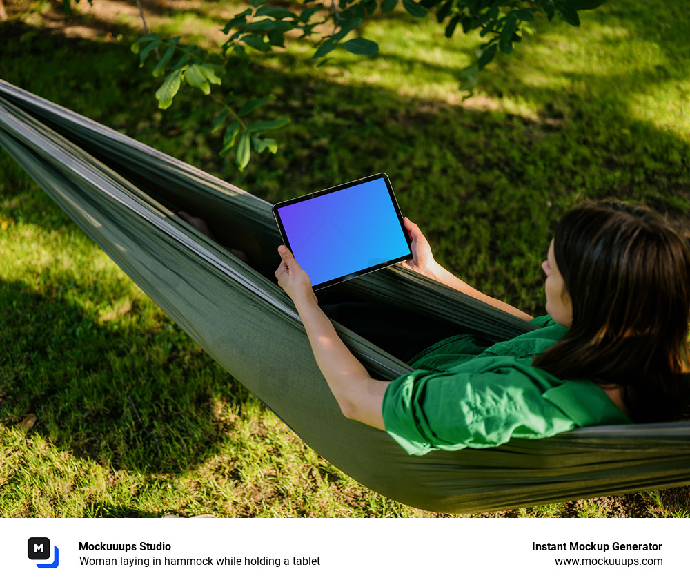 Woman laying in hammock while holding a tablet