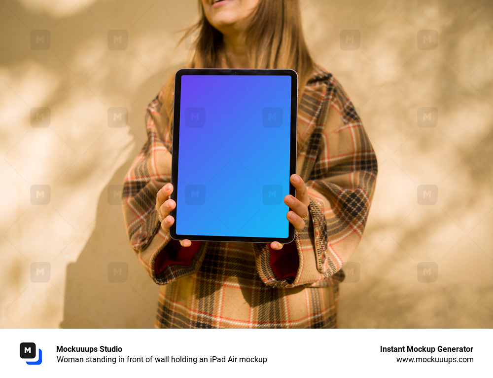 Woman standing in front of wall holding an iPad Air mockup