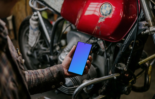 Man holding a Pixel 6 mockup beside a motorcycle