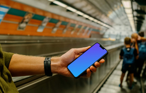 Man holding iPhone 13 mockup in subway