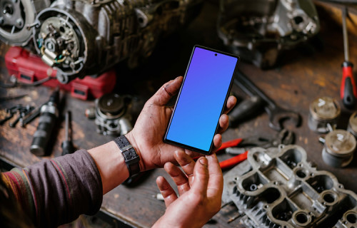 Man holding Pixel 6 mockup in a mechanic shop