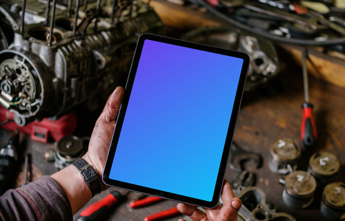 Man holding up an iPad Air mockup in front of a workbench