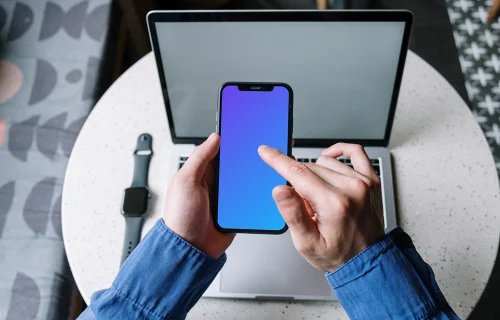 User in blue shirt typing on an iPhone 12 mockup