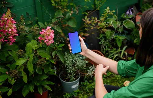 Mulher segurando um iPhone mockup com flores ao fundo