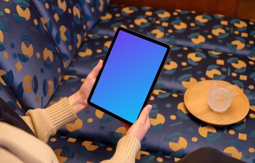 Female holding iPad mockup in colorful lounge setting