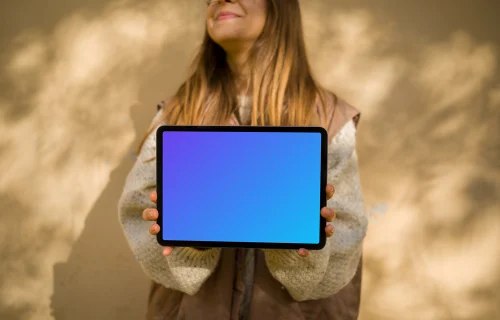 Mujer con chaleco de otoño sosteniendo un iPad Air mockup