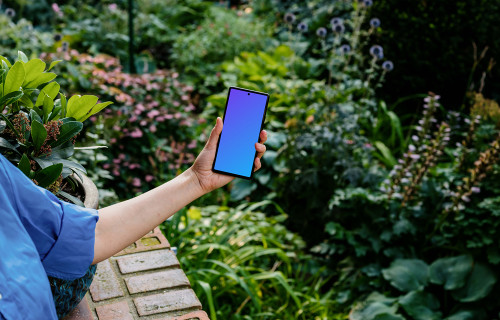 Hand holding a phone mockup with background full of plants