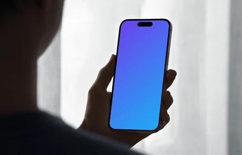 iPhone 15 Pro mockup in a male hand against soft backlight