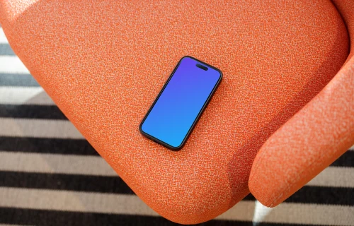 iPhone 15 Pro mockup on a vibrant orange armchair