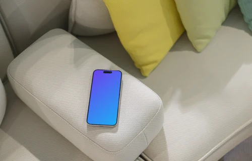 iPhone 15 Pro mockup on modern couch with colorful cushions