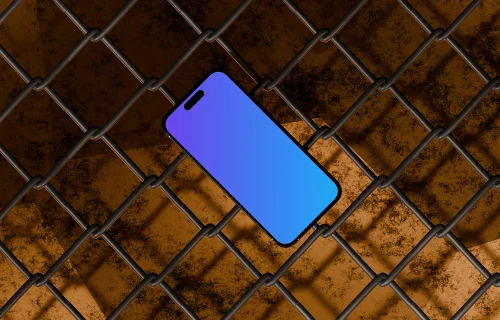 iPhone 16 Mockup Against Industrial Chain-Link Fence