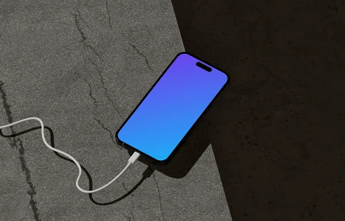 iPhone 16 Mockup on Concrete Surface with Charging Cable