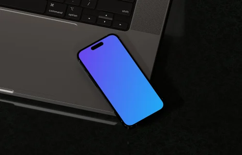 iPhone 16 mockup with laptop on black surface