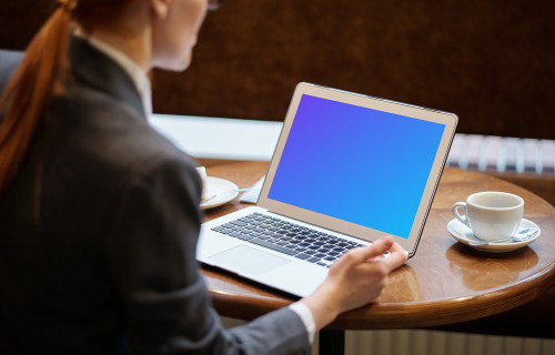 Senhora usando um MacBook Air mockup com uma xícara de café ao lado