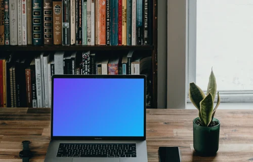 MacBook Pro mockup beside a smartphone and potted plant