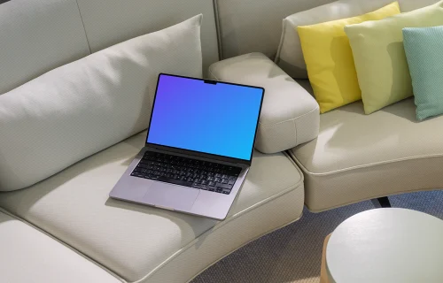 MacBook Pro mockup on a modern beige sofa with colorful pillows