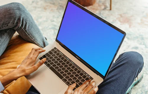 Usuário do sexo masculino sentado em uma cadeira e usando um MacBook Pro mockup