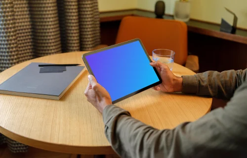 Hombre con un iPad en la mano mockup en el salón