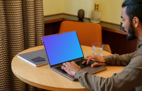 Man typing on a MacBook Pro mockup in a lounge