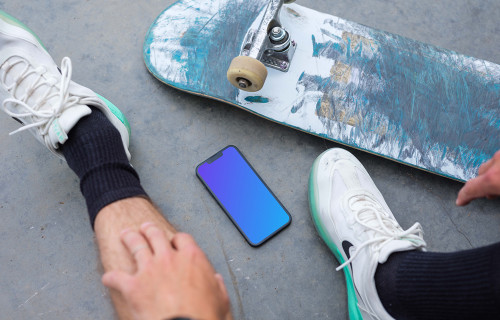 Skateboarder sitting next to an iPhone 13 mockup