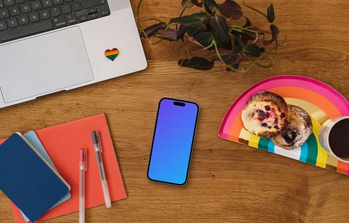 Smartphone mockup on a wooden table next to the rainbow tray with cakes