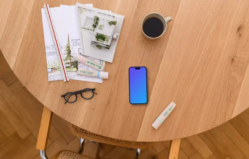 Smartphone mockup with architectural blueprints on wooden table