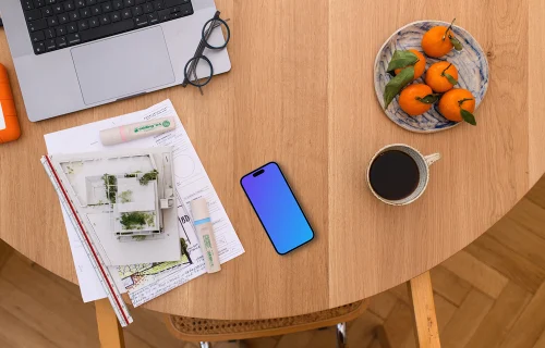 Smartphone mockup with architectural plans on a wooden table