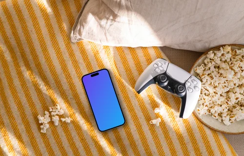 Smartphone mockup with gaming controller and snacks on cozy sofa