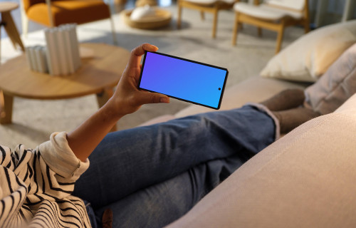 Woman hand holding a phone while laying on a couch