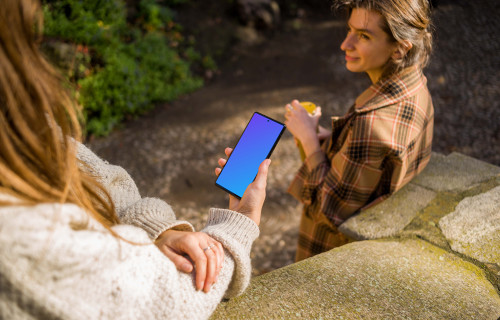 Woman holding a Google Pixel 6 next to a friend mockup