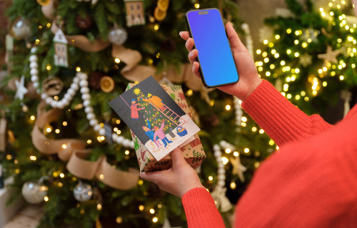 Mujer sosteniendo un teléfono y un regalo de Navidad