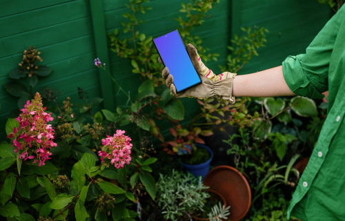 Woman holding a phone in garden gloves mockup