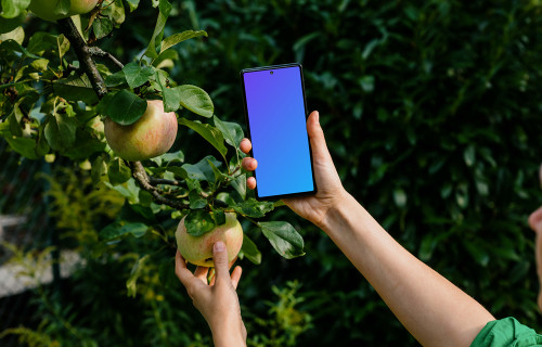 Woman holding a phone while taking an apple from tree mockup