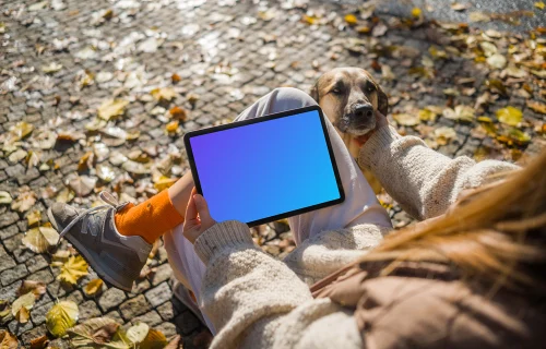 Mujer con una tableta en el parque rascando perro mockup