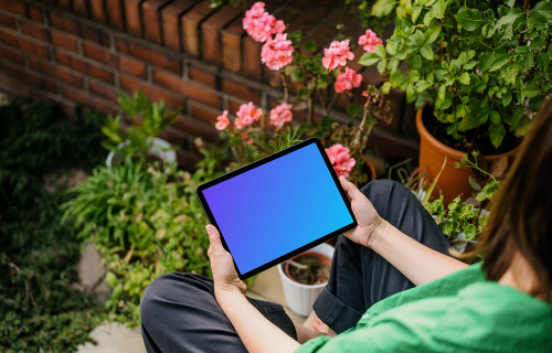 Woman holding an iPad Air in garden full of plants