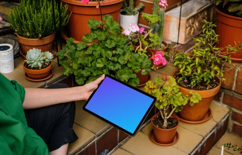 Mulher segurando um iPad Air mockup e cuidando de flores