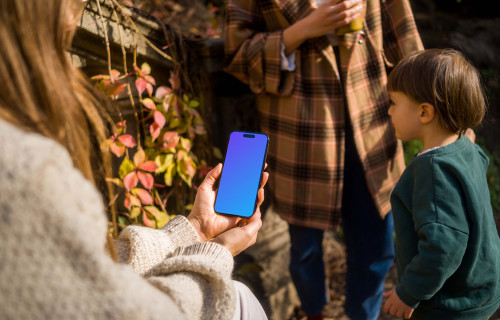 Woman holding an iPhone 14 Pro in garden mockup