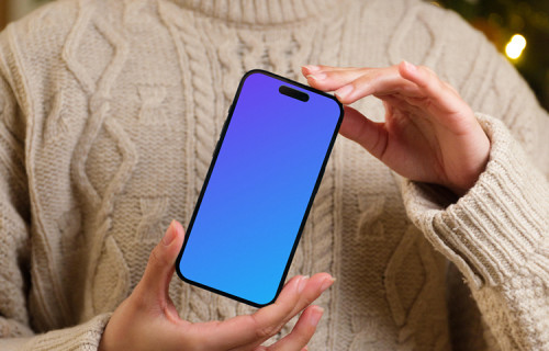 Femme tenant un iPhone 14 Pro mockup à côté du sapin de Noël