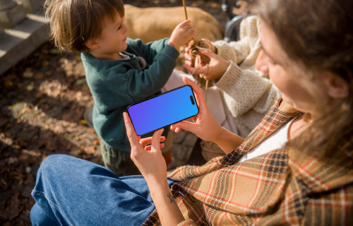 Woman holding an iPhone 14 Pro while sitting on a bench mockup